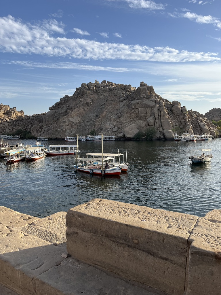 Traditional wooden motorboats docked on the Nile River with the rocky landscape of Agilkia Island in the background, Aswan, Egypt