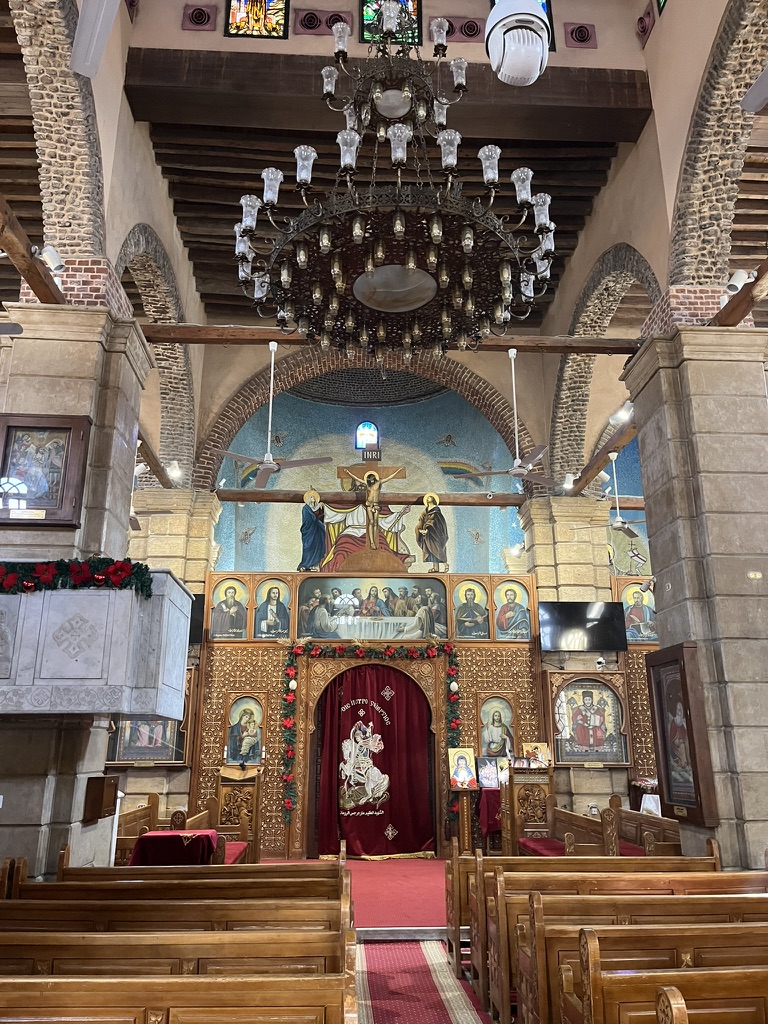 The interior of the Church of St. Sergius and Bacchus in Coptic Cairo features a traditional timber-roofed ceiling, a marble ambon, and an intricate iconostasis adorned with religious icons.