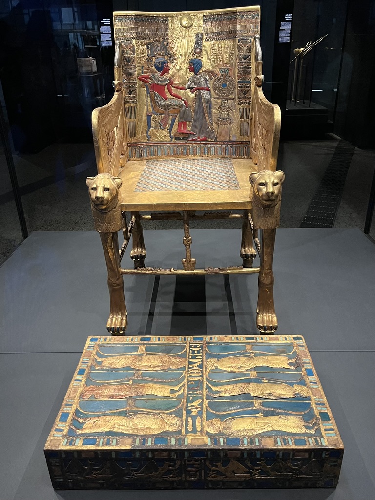 The backrest depicts an intimate scene of Queen Ankhesenamun anointing the King under the rays of the Aten sun disk.