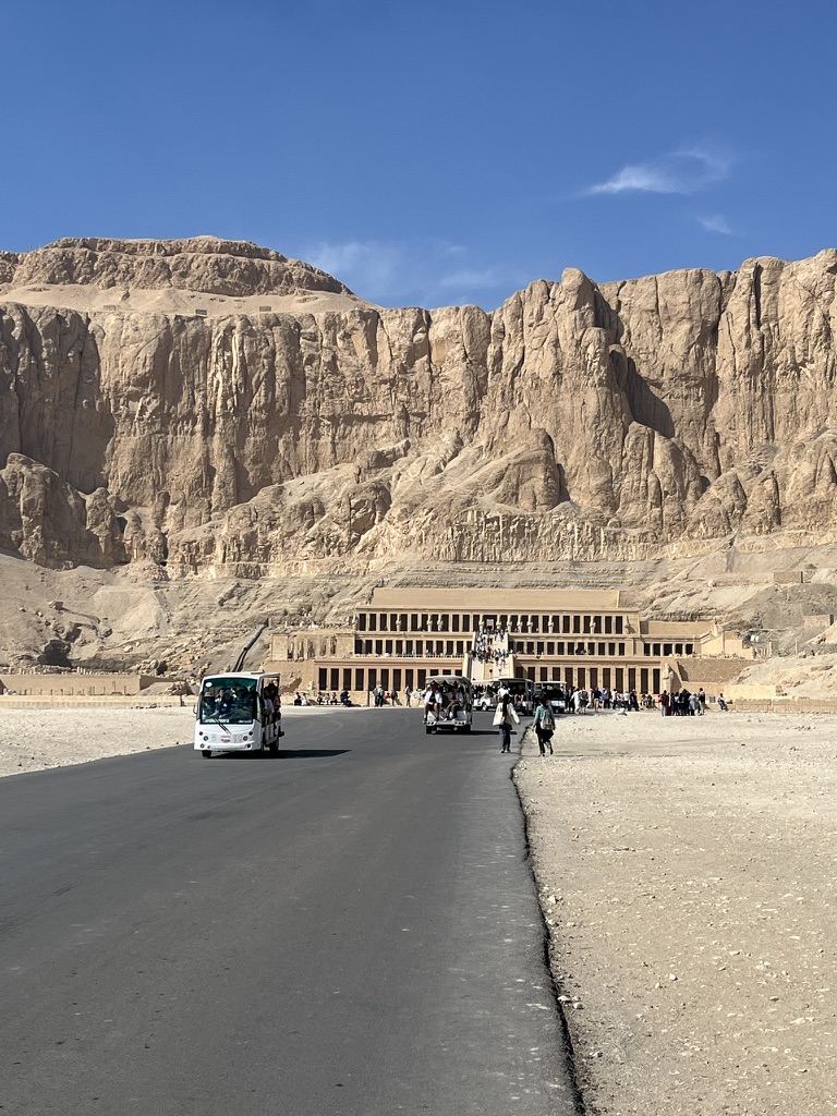 A wide view of the three-tiered mortuary temple of Queen Hatshepsut, built directly into the towering limestone cliffs of the Theban Necropolis.