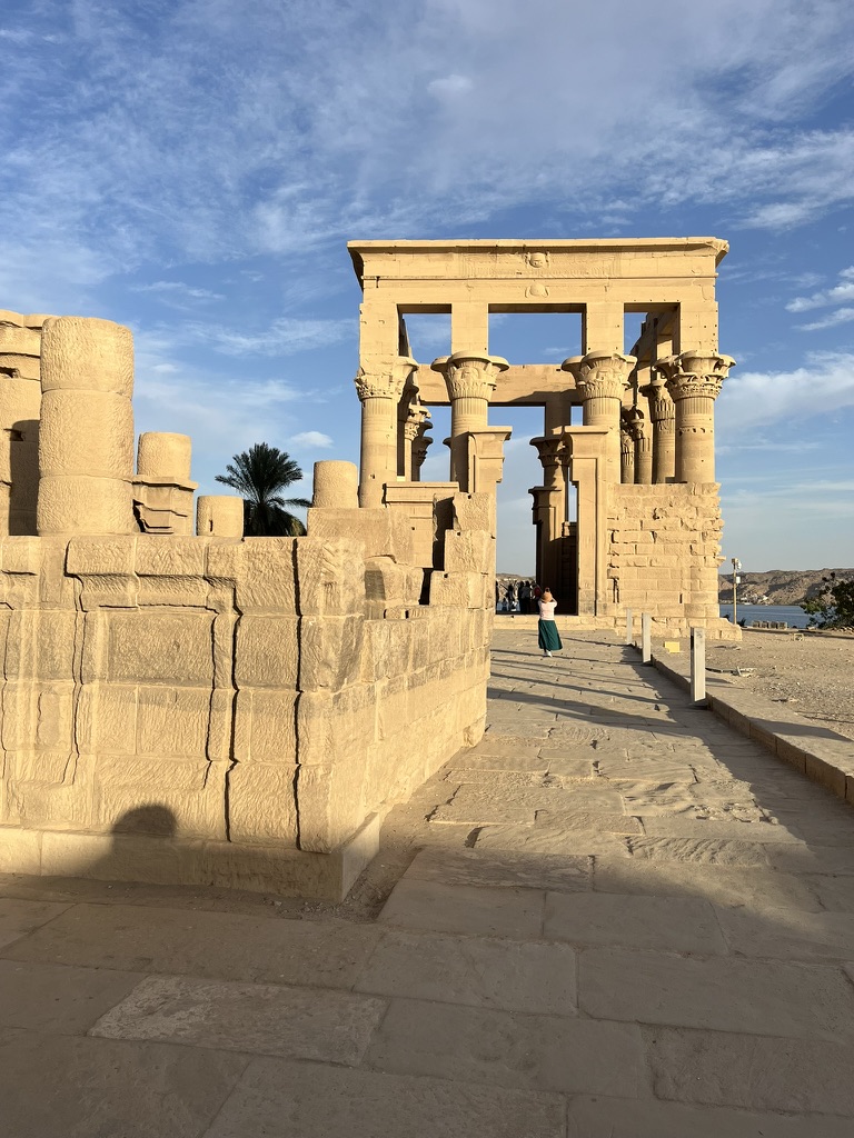 Trajan's Kiosk at Philae Temple in Aswan, an open-air stone structure with ornate floral columns reflecting the afternoon sun.