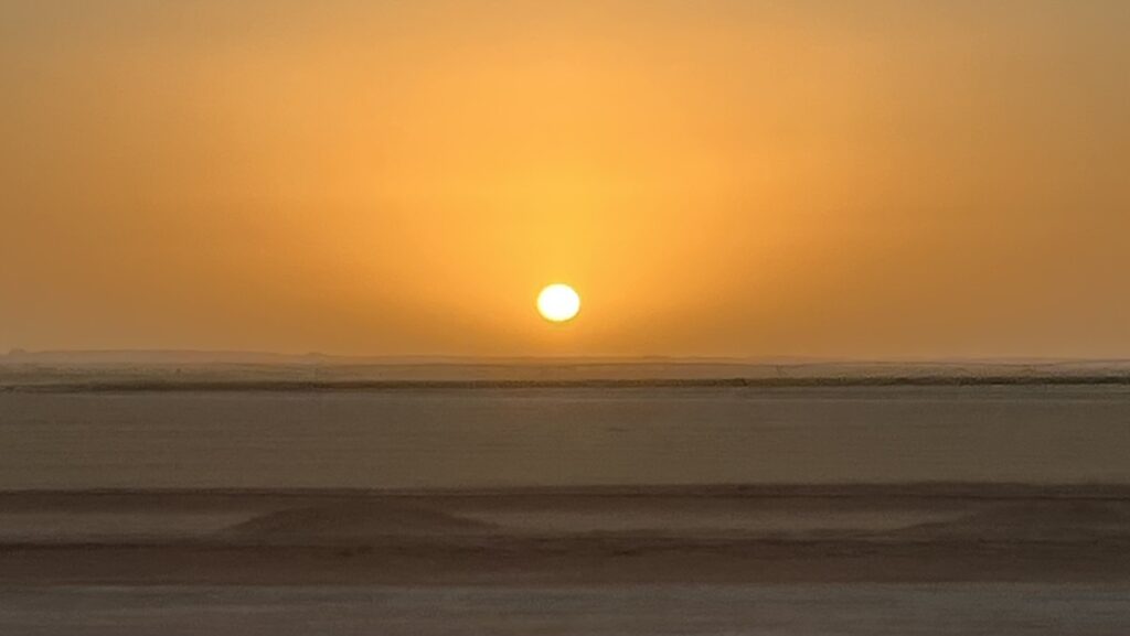 A pre-dawn start to the 280-kilometer drive, with the sun beginning to rise over the vast desert horizon.