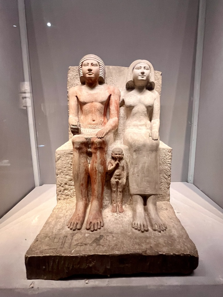 The monumental seated statue of Pharaoh Amenhotep III and his Great Royal Wife, Queen Tiye, with their daughter, Princess Henuttaneb, standing between them.
