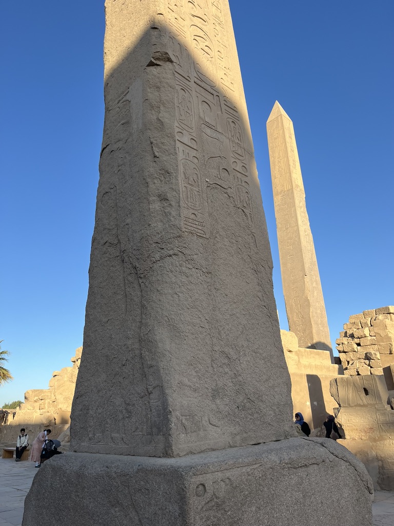 The Great Court at Karnak featuring the pink granite obelisks of Thutmose I and Queen Hatshepsut.