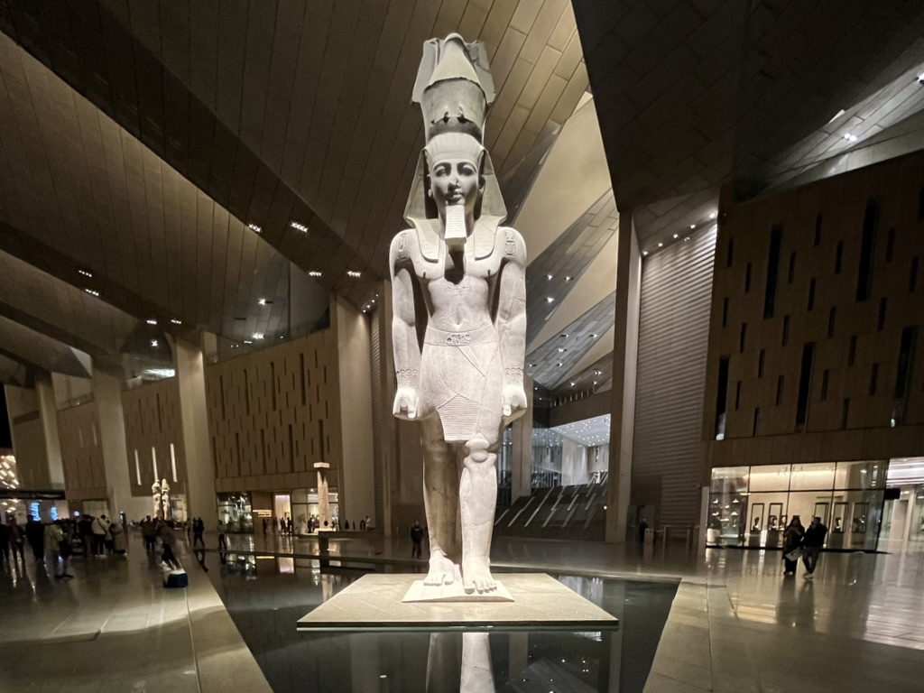 The Colossus of Ramesses II, a massive granite statue standing in the grand atrium of the Grand Egyptian Museum.