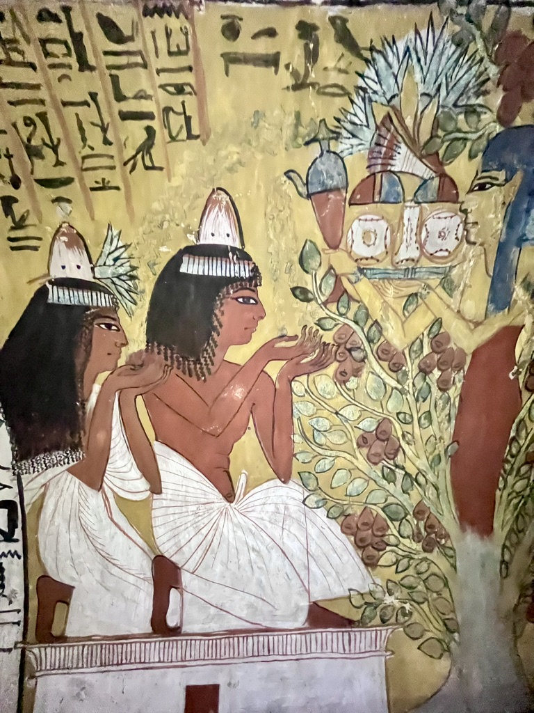 A detailed fresco showing a deceased couple kneeling in prayer as they receive liquid offerings and nourishment from the sky goddess Nut, who emerges from a sycamore fig tree.
