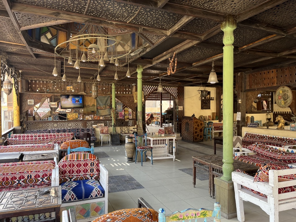 Cairo Attractions Guide: A colorful and cozy corner in a local restaurant, where vibrant "khayamiya" fabrics and intricate woodwork set the stage for a classic Egyptian meal.