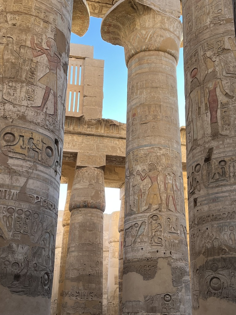 The Hypostyle Hall at Karnak Temple features towering sandstone columns decorated with intricate hieroglyphs and religious reliefs.