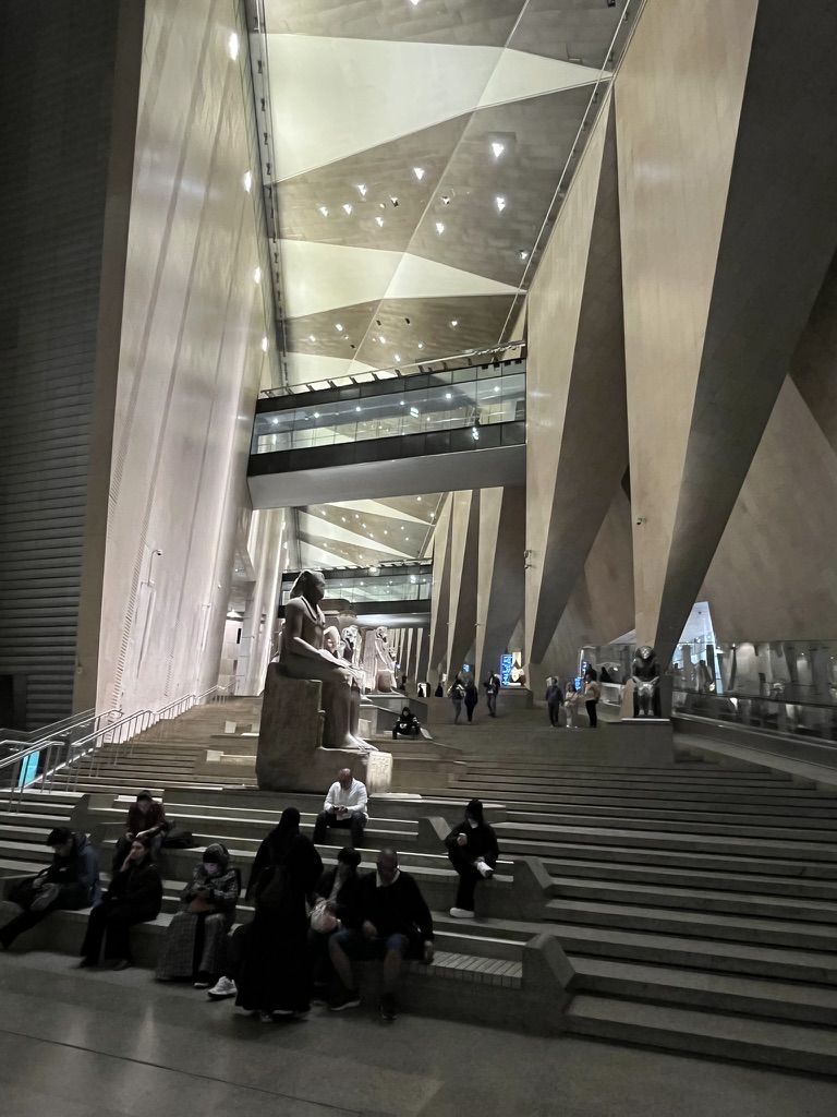 The Grand Egyptian Museum contains a massive tiered staircase lined with monumental statues of ancient Egyptian pharaohs and deities.