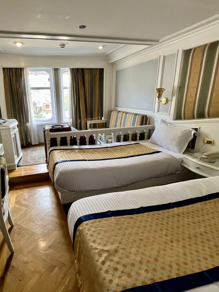 A standard twin-bed cabin on a Nile cruise ship, featuring traditional wood-paneled decor and parquet flooring.
