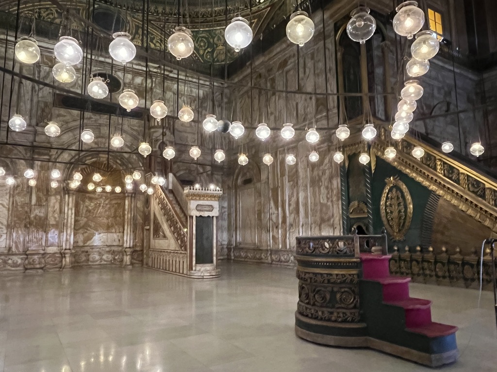 Egypt Itinerary Options: The Great Mosque of Muhammad Ali features an ornate interior illuminated by a circular arrangement of glass globes hanging from the ceiling.